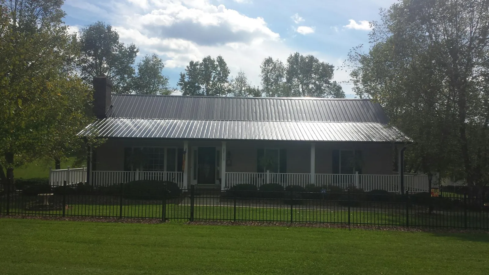 Gray metal roof on a brick ranch with a full width front porch — Gutter Guard Installation work by our crew in Berea