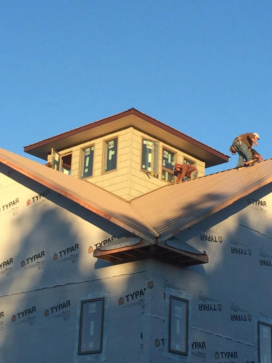 Roofers working around a rooftop cupola on a new metal roof at sunset — Roof Waterproofing in Berea by Roofing Brothers